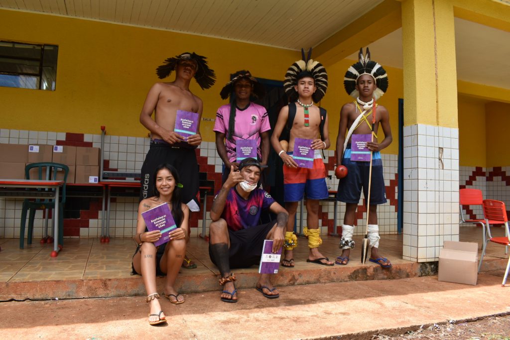 Jovens Kaingang mostram o livro que conta histórias da comunidade