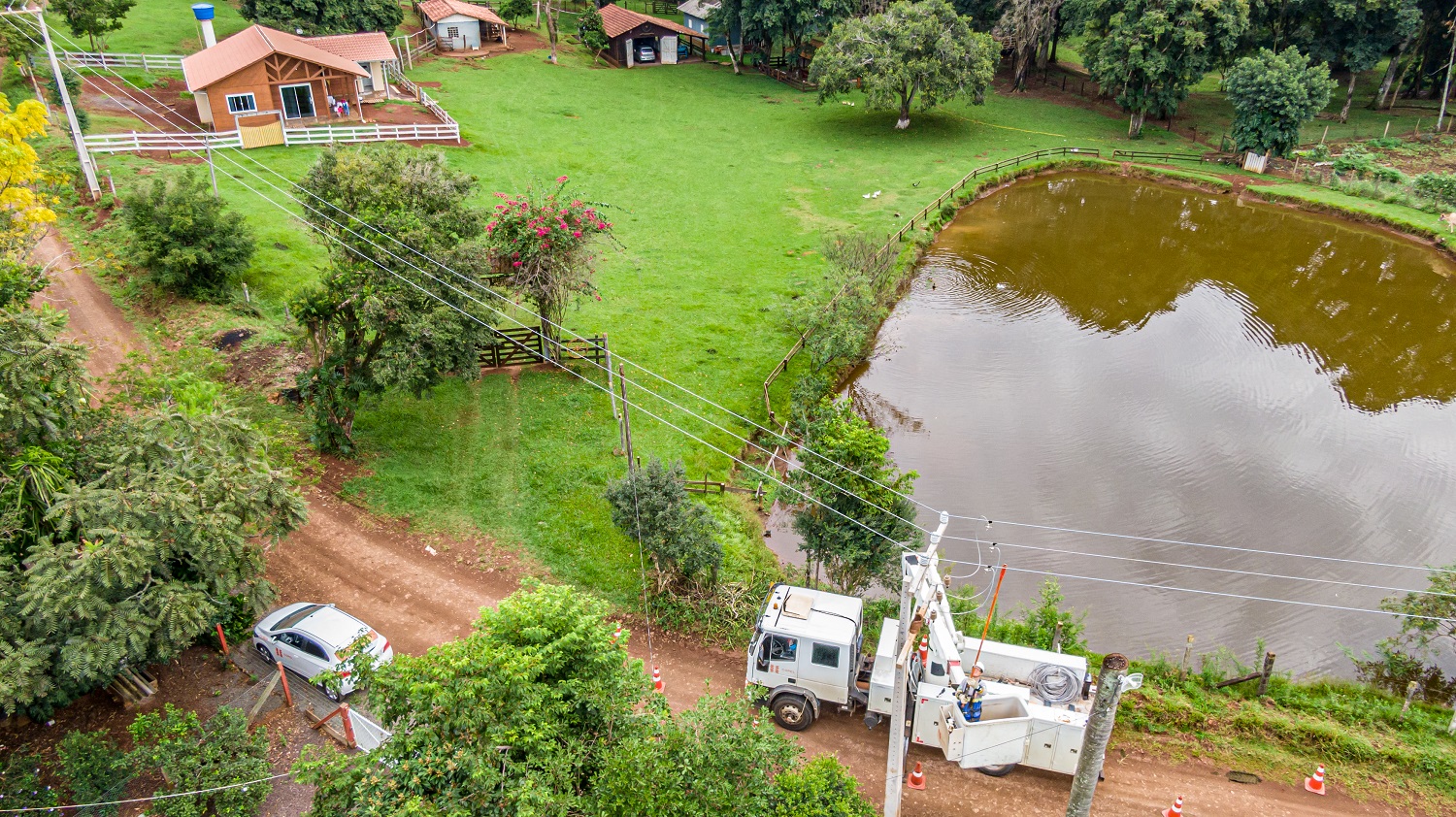 Obra do Paraná Trifásico rede elétrica ao lado de lago na área rural