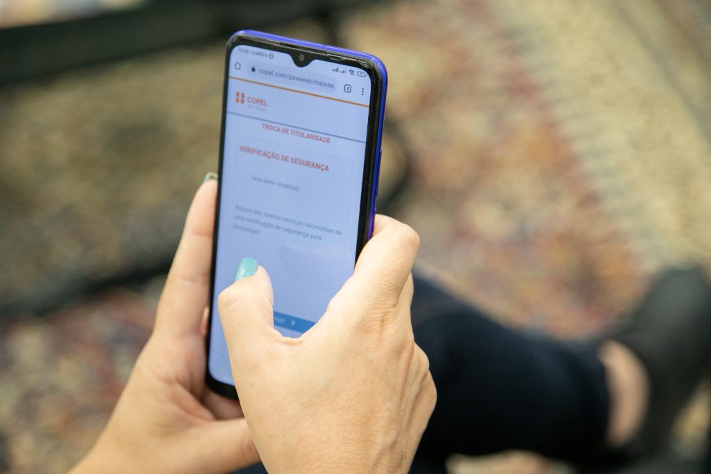 Duas mãos segurando celular com aplicativo da Copel aberto