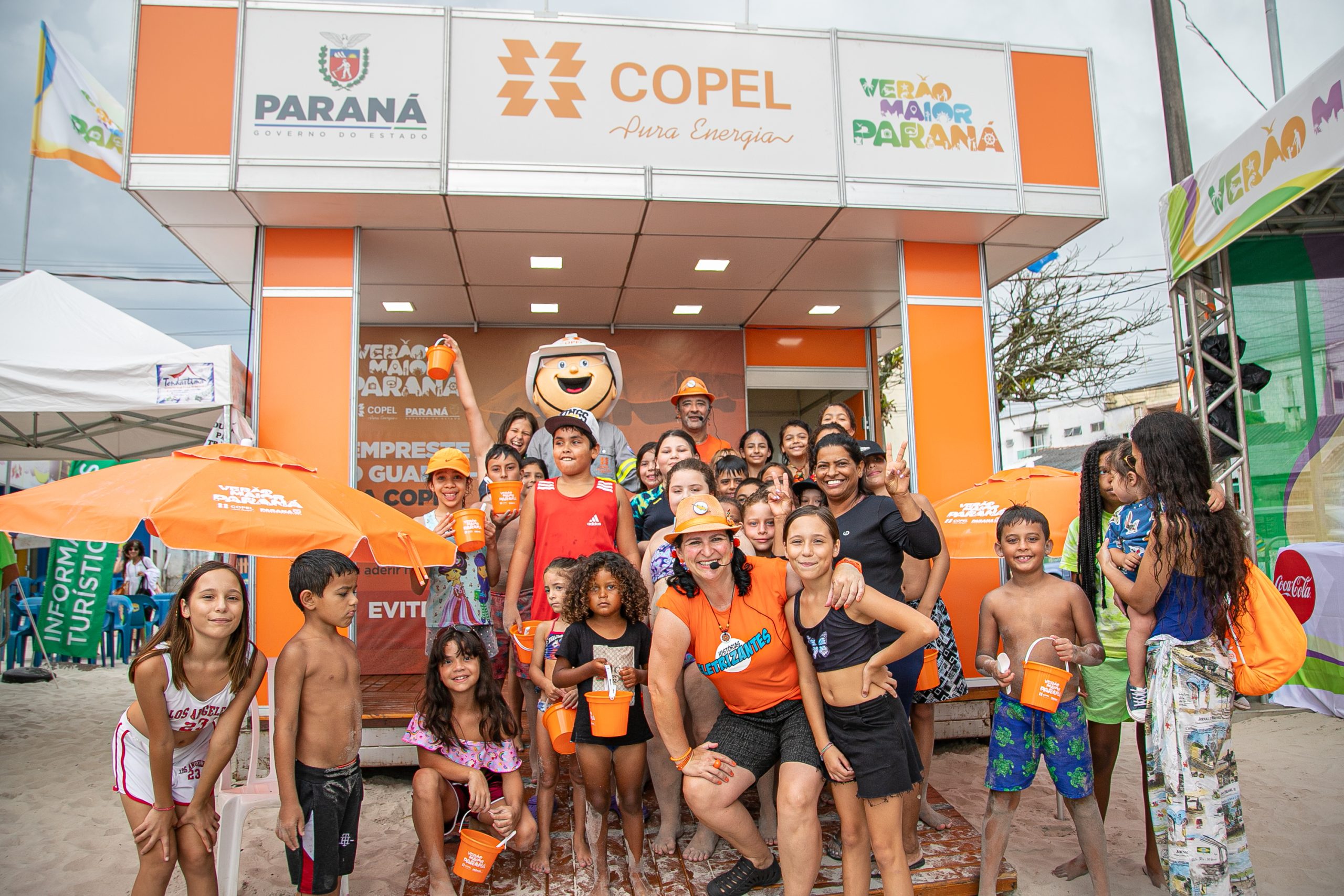 Atores da Copel reunidos com o grupo de crianças em frente à estação da Companhia na orla da praia