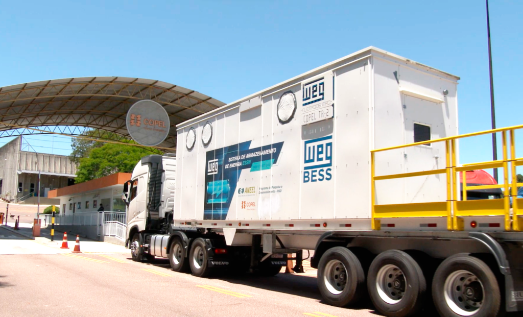 Bateria branca adesivada em azul sobre uma carreta chegando às instalações da Copel no bairro Atuba em Curitiba